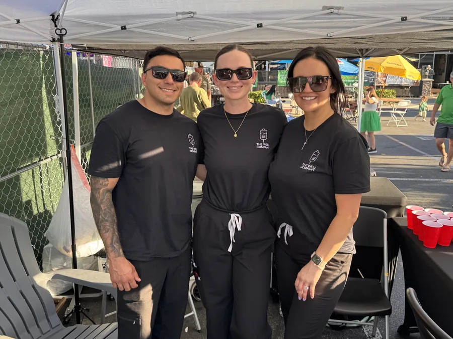 The Well Company team in branded shirts at a community event under their pop-up tent