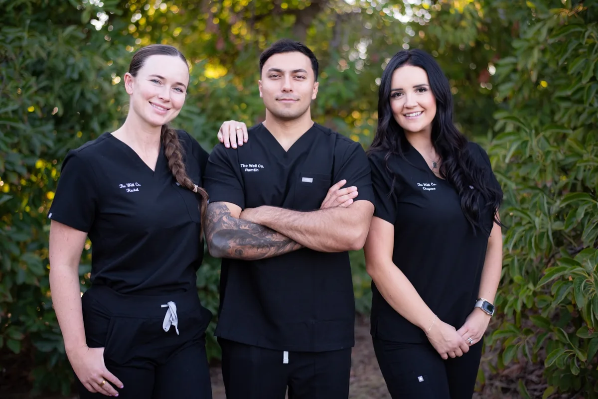 The Well Company team of three, in branded black scrubs, outdoors